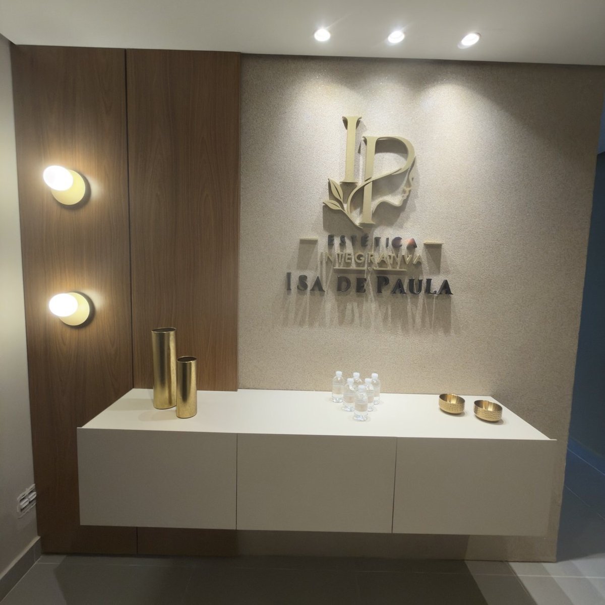 Recepção da clínica Isa de Paula, com a logo aplicada na parede e marcenaria clara